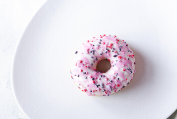 Delicious donut with fresh summer berries on white textured plate.