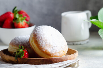 Fresh doughnut for breakfast on wooden plate.