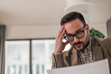 Fototapeta premium Close-up of tensed young professional analyzing document while working at office