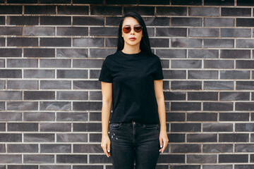 Stylish brunette asian girl wearing black t-shirt and glasses posing against street , urban clothing style. Street photography	

