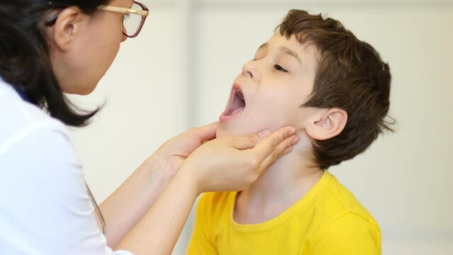 medical examination. Pediatrician feels the tonsils in a child with a sore throat and shows his tongue