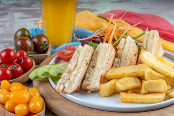 Traditional sandwich made from slices of toasted bread, cheese served with orange juise ,fried patatoe, salads and different colors of tomatoes.