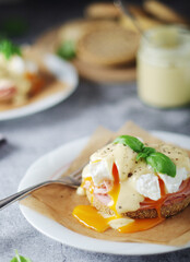 Egg benedict sandwiches - muffin with poached egg, ham and hollandaise sauce