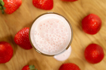 Glass cup with strawberry milkshake smoothie, fruit juice with milk is poured close up. Selective focus