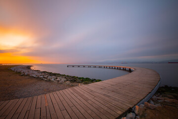 The pier like a boomerang at sunrise was captured with the long exposure technique.