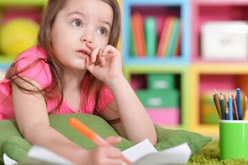 Portrait of cute little girl in pink shirt drawing