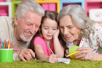 Portrait of grandparents playing with their grandaughter while lying on floor