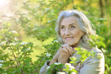 Beautiful senior woman posing near blooming tree