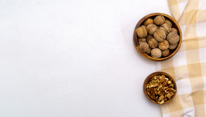 Walnuts in a wooden bowl on a white background with a copy space. View from above. Space for text