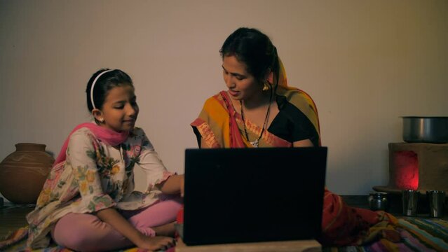 Young mother learning to run a laptop from her daughter - modern villager. Indian rural housewife enjoys learning modern technology from her daughter during her free time - village lifestyle