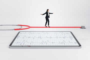 Pretty young european businesswoman walking on stethoscope above tablet with cardiology screen on light background. Medicine and doctor, healthcare concept.