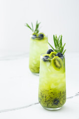Refreshing drink with kiwi smoothie, summer sweet fruit juice with blueberries and rosemary
