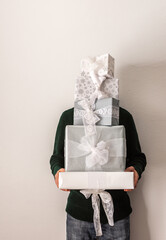 Preparing for the holiday, a man holds white and silver gift boxes in front of him