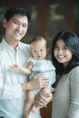 young Asian family are happy together at home by life insurance concept, child baby and mother and father having fun and smile with love, childhood living in cozy lifestyle with dad and mom
