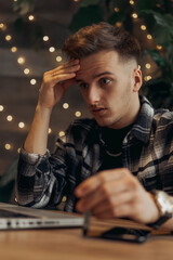 Confused and bewildered businessman looking at screen of laptop and working on project remotely in coffee shop  