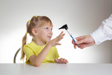 The doctor examines the ear canal of a little caucasian girl 5 years old in the doctor's office....