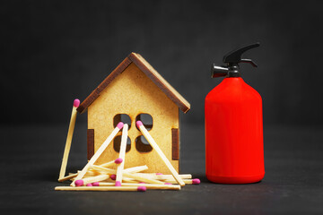 Fire extinguisher and matchsticks by a toy house