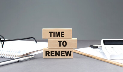 TIME TO RENEW text on wooden block with notebook,chart and calculator, grey background