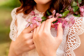 girl holding blosoming apple tree branch with pink flower in spring orchard, hands close up