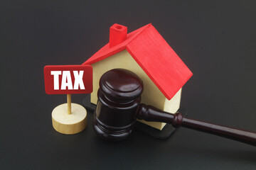 Pay tax for real estate concept. Judge gavel with wooden house and banner with word TAX.