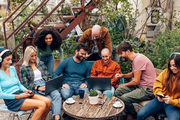alternative young boys sit on the terrace of the youth hostel or student dormitory bar talking and...