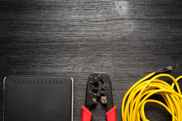 Computer network cable crimper, switch and cable on the black flat lay background with copy space.