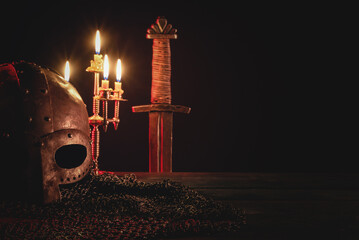 Ancient sword, armor and helm on the wooden table background. Front view.