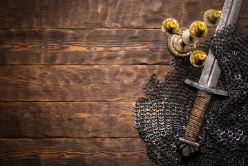 Ancient knight sword and armor on the wooden table flat lay background with copy space.