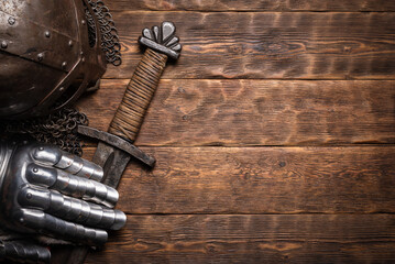 Ancient knight sword and armor on the wooden table flat lay background with copy space. - obrazy, fototapety, plakaty