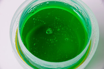 Gel for washing things in a transparent green dispenser on a white background close up