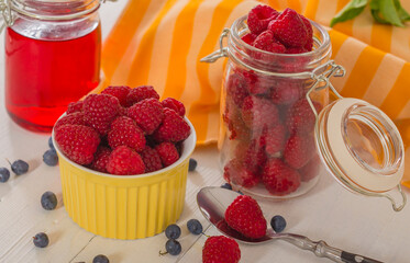 Raspberries in a yellow bowl and two jars