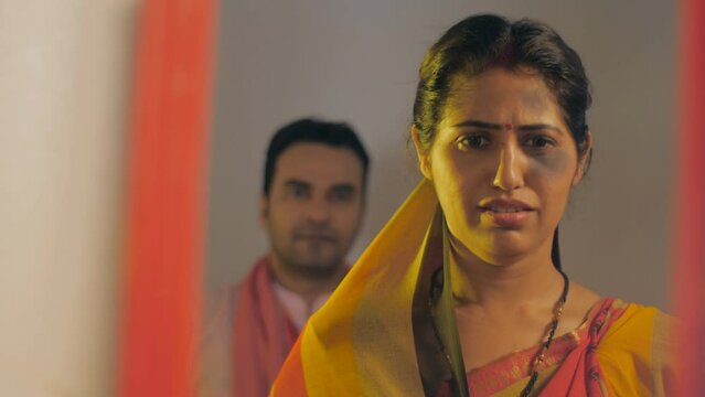 Aggressive Indian husband scolding and threatening his wife after domestic violence. Village housewife wearing saree with bruises and scars - drink husband shouting and fighting