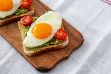 Homemade Healthy Egg, Avocado and Tomato Toast on a rustic wooden board, side view. Space for text.