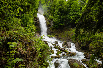 Naklejka na ściany i meble Beautifull large waterfall in the Swiss Alps. Sunny summer day, green nature, no people