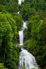 Fototapeta na wymiar Giessbach waterfall in the Swiss Alps, Canton of Bern. Sunny summer day, green nature, no people