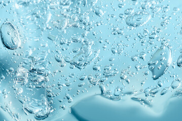 Close up macro Aloe vera gel cosmetic texture blue background with bubbles. Lemongrass gel skincare...