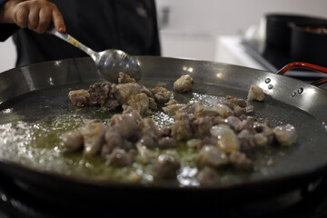 chef cocinando carne en paellera