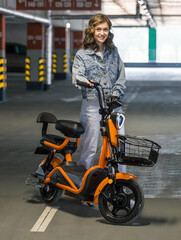 Fototapeta na wymiar beautiful girl posing sitting on an electric scooter in the parking lot