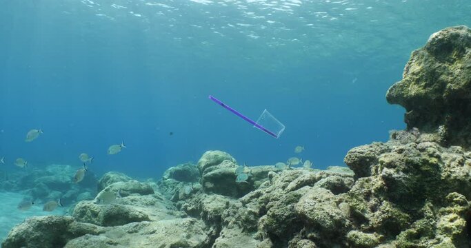 plastic waste underwater bad for fish with sun rays water waves hit to rocks background ocean pollution