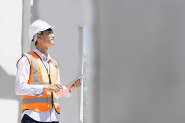 A civil engineer  Asia or architect with a hardhat on a construction site checks the schedule on a computer tablet.