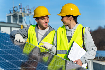 Waist up portrait view of young solar panel worker looking at his female colleague, while talking about peculiarities of process of obtaining alternative energy