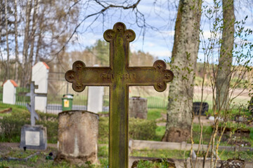 Ancient metal cross in the Latvian cemetery. Sunny day.