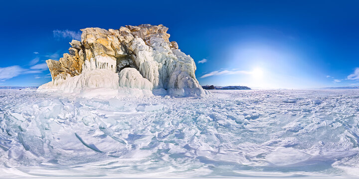 Shaman Rock or Cape Burhan on Olkhon Island in winter, surrounded by the blue ice of Lake Baikal with cracks. Panorama 360 180 degree