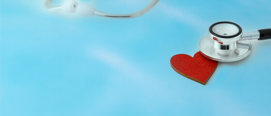 Stethoscope head on red heart on blurred blue background. Healthy heart day.