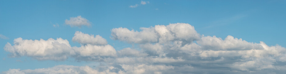 Banner with panoramic view over deep blue clean sky with illuminated clouds as a background.