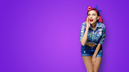 Happy excited woman holds hand near open mouth, looking aside and saying something. Girl dressed in pinup style. Red purple haired pin up model at retro fashion vintage concept, violet background.