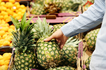Man buying  pineapple at the market - Powered by Adobe