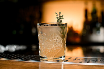 Close-up view of glass with cocktail garnished with rosemary on blurred background