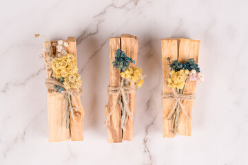 Palo santo sticks decorated with dried flowers over white marble table background. Holy wood sticks for meditation and spiritual practices. Esoteric ceremony. Mental health concept