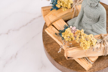 Palo santo sticks with Buddha statue in a meditation room on white marble table background with copy space. Incense for yoga, meditation and spiritual practices